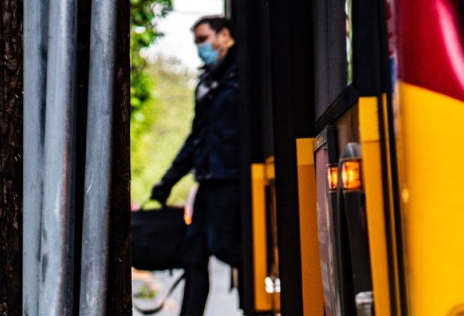 Man wearing face mask stepping off a bus