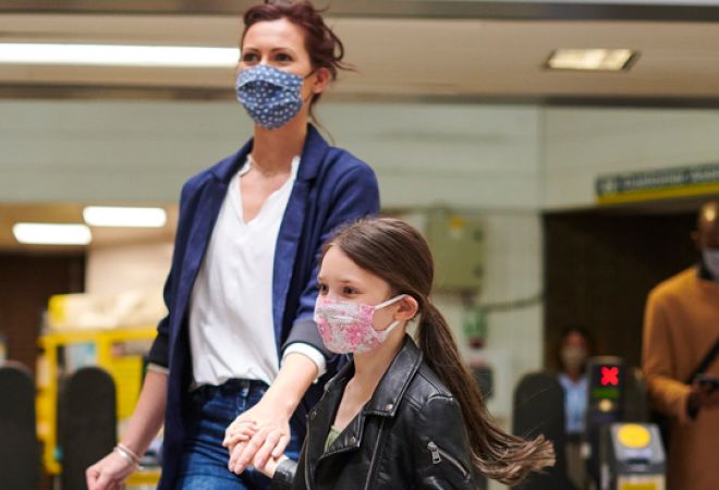 Mother & daughter wearing face masks in train station
